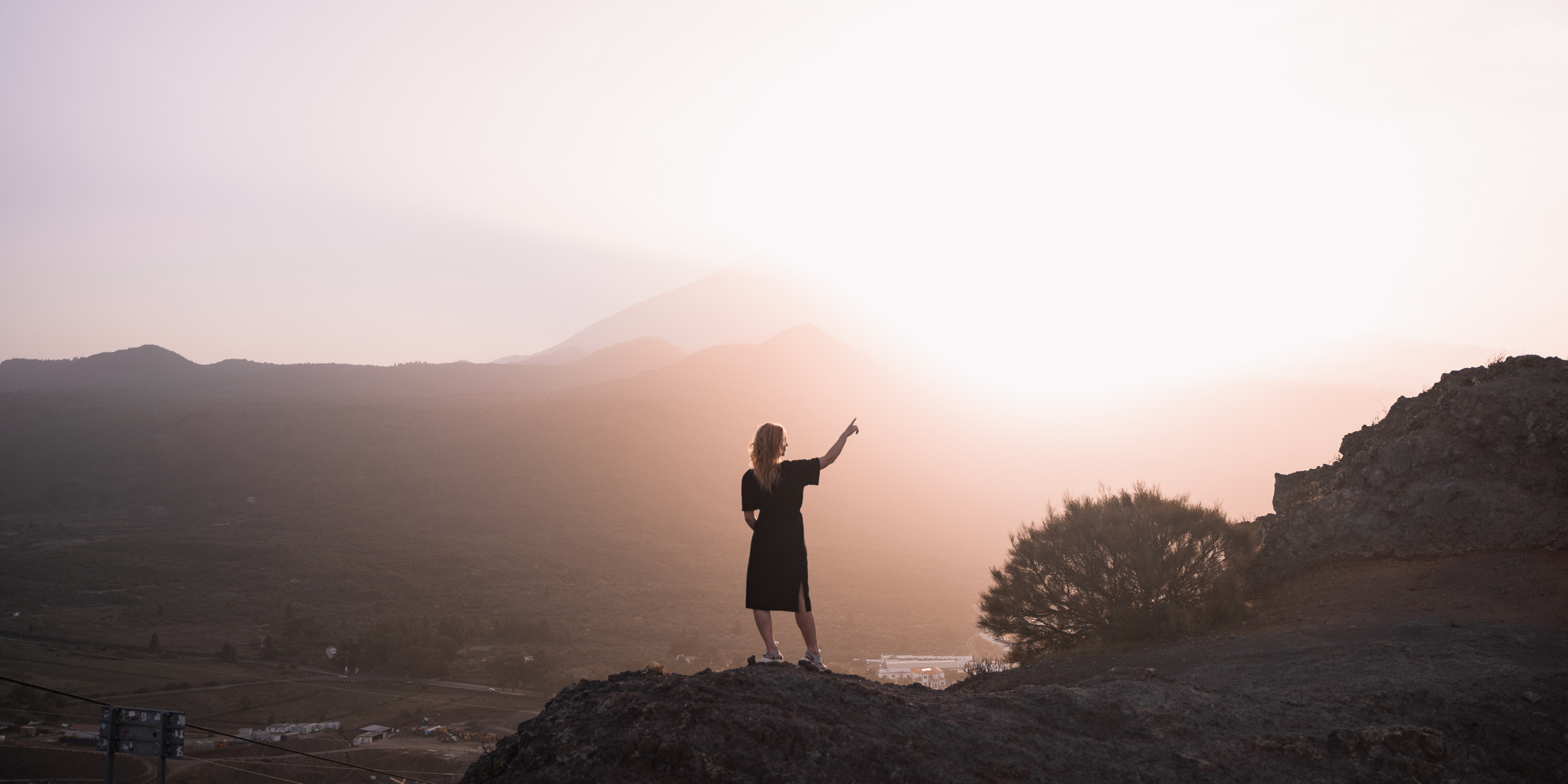 Female traveller watching sun set in a reversible black dress. Circular travel capsule wardrobe with sustainable and interchangeable clothing for travelling light, created for a minimal wardrobe and travelling in a carry-on only to avoid packing headache.