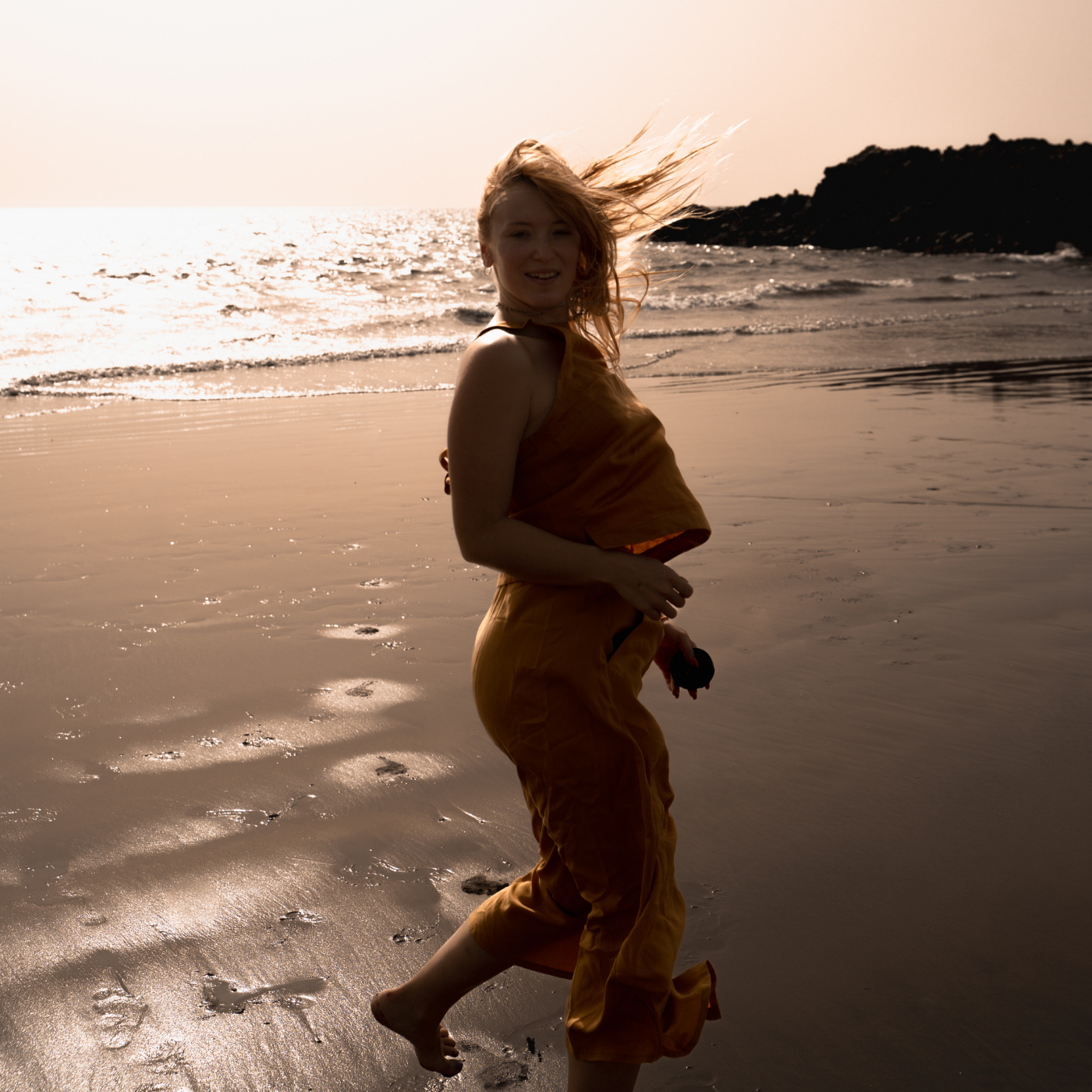 Woman on the beach in yellow clothes and dress. Circular fashion for travellers with versatile and interchangeable clothing to explore.