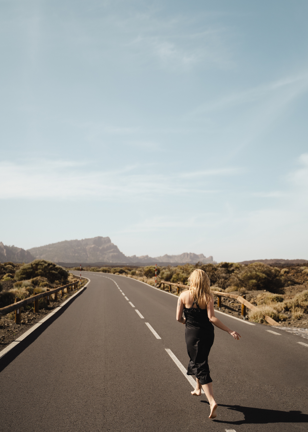 Woman running through the street in a black dress. Circular travel capsule wardrobe with sustainable and interchangeable clothing for travelling light, created for a minimal wardrobe and travelling in a carry-on only to avoid packing headache.
